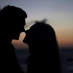 The Silhouette of a Couple Standing Nose to Nose While Standing Against a Setting Sun
