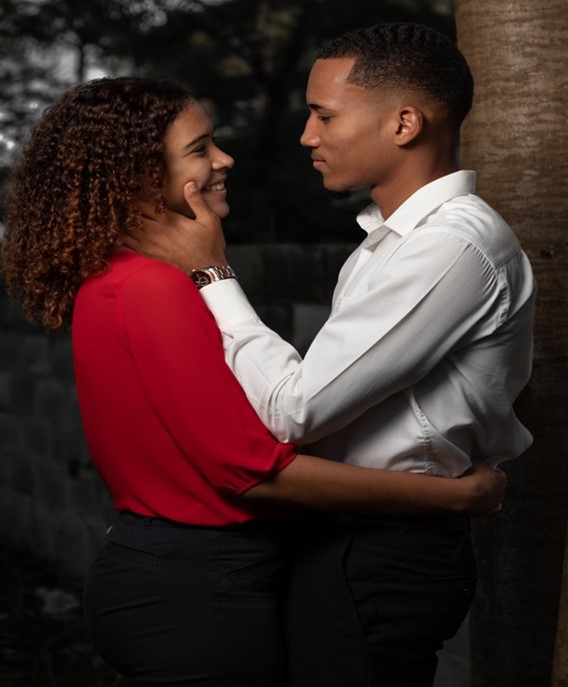 A Man in a White Button-Down Caressing the Face of a Visibly-elated Woman in a Red Top